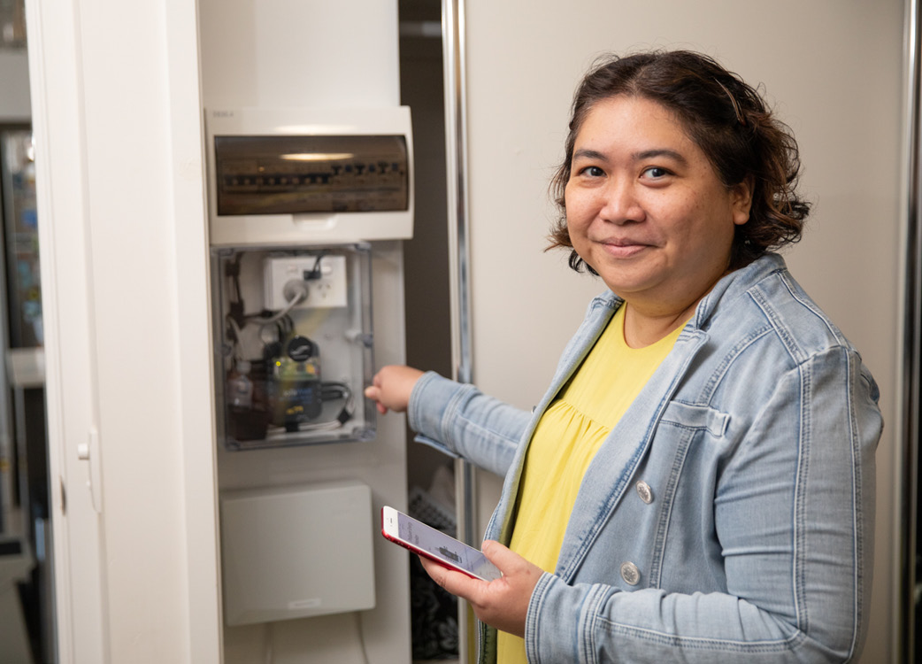 A woman standing in front of an electricity switchboard