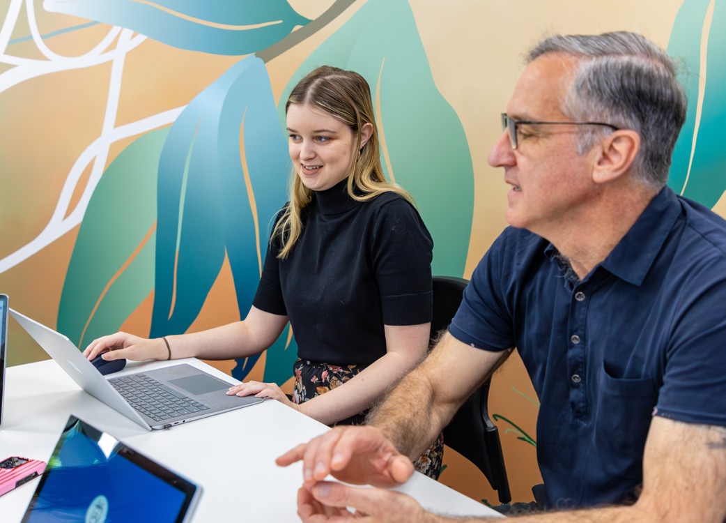 A man and a woman looking at a laptop in a meeting room